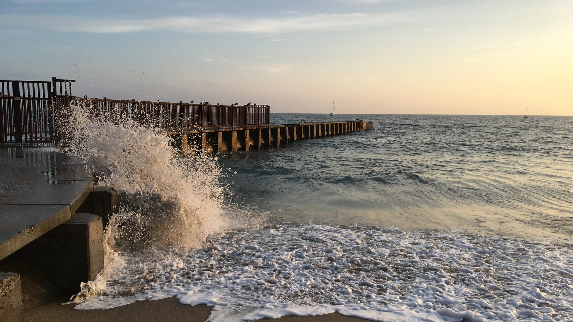 Waves crash against a jetty in Playa Del Rey, California, at sunset.