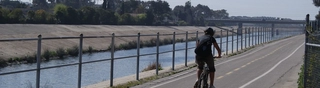 A person bicycling next to river